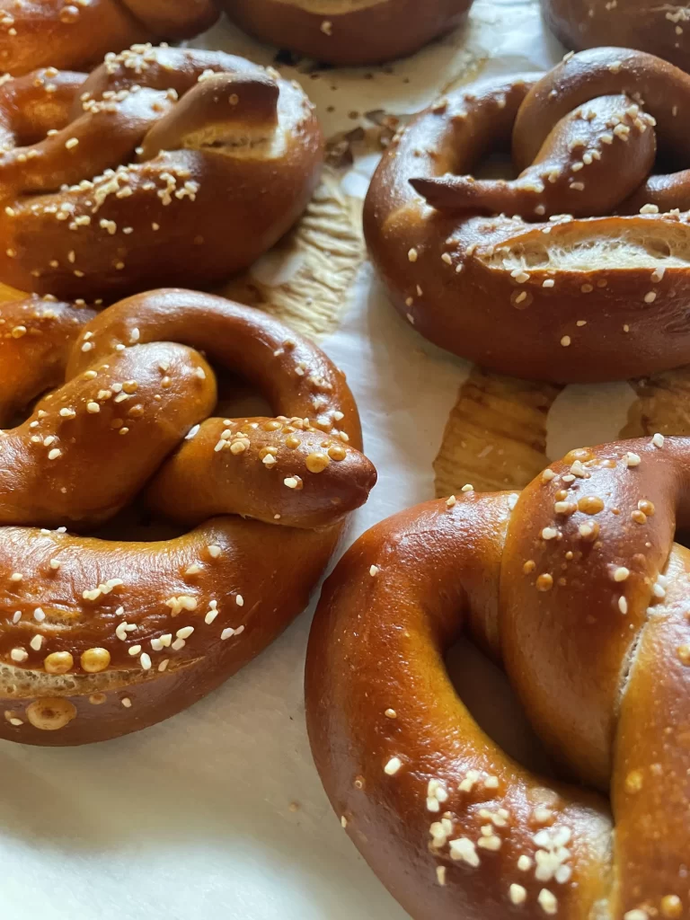 Close-up of freshly baked pretzels sprinkled with sesame seeds on parchment paper.